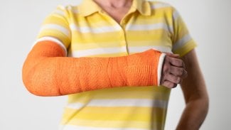 Detail ženy, která má levou ruku v odlehčené fixaci zlomenin