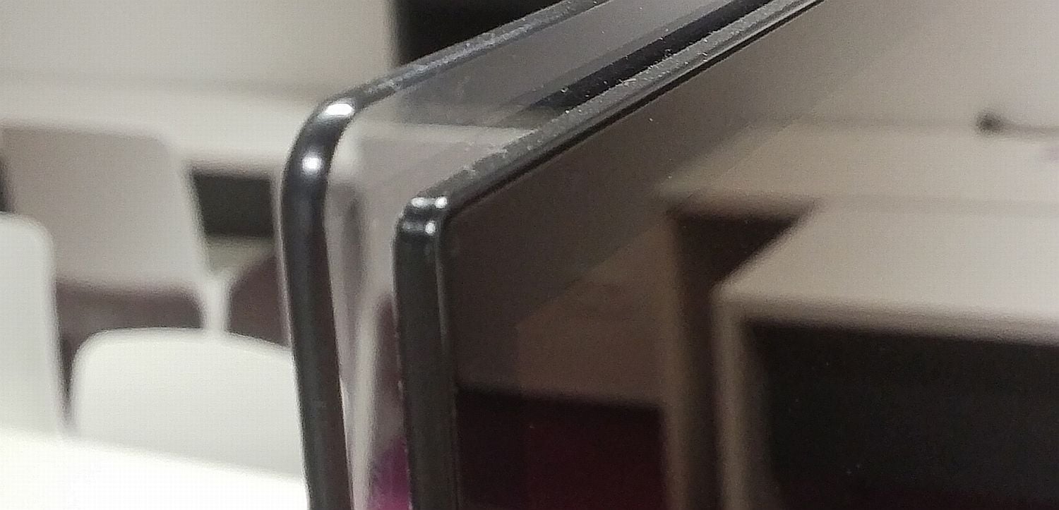 Vpravo lesknoucí se obrazovka, vlevo skleněná deska, na které je nalepena.