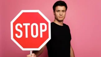 Muž, který drží v ruce značku STOP