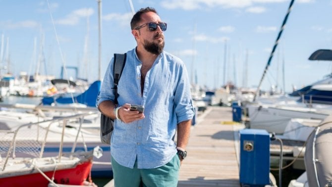 Muž v přístavišti drží mobilní telefon