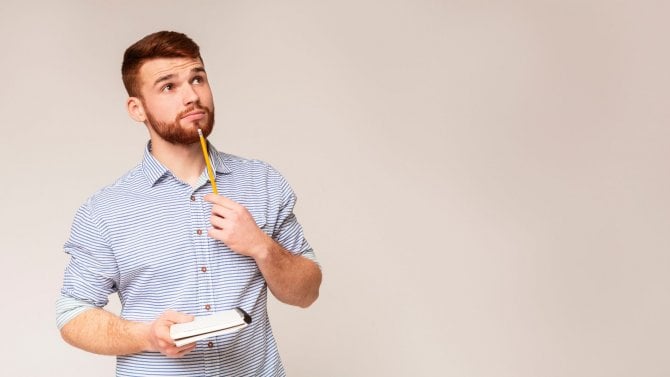 Přemýšlející muž, který drží v ruce blok a tužku.