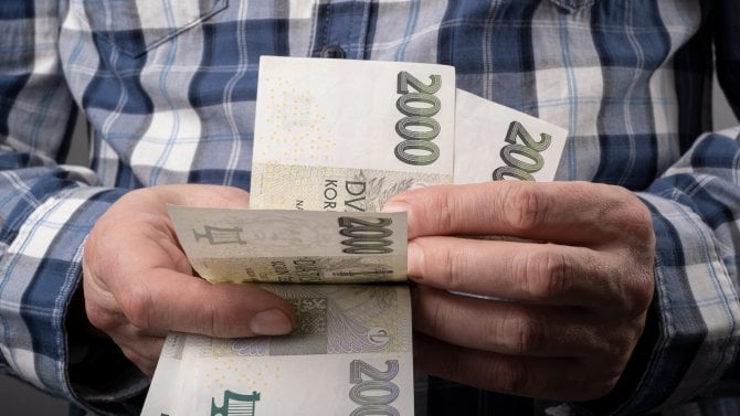 Detail rukou držících dvoutisícikorunové bankovky