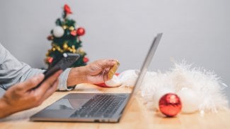 muž nakupující online na Štědrý den pomocí smartphonu doma nebo v kanceláři. muž používající mobilní telefon v interiéru k zaplacení zboží na vánoční svátky. e-commerce, online nakupování z domova, vánoční koncept