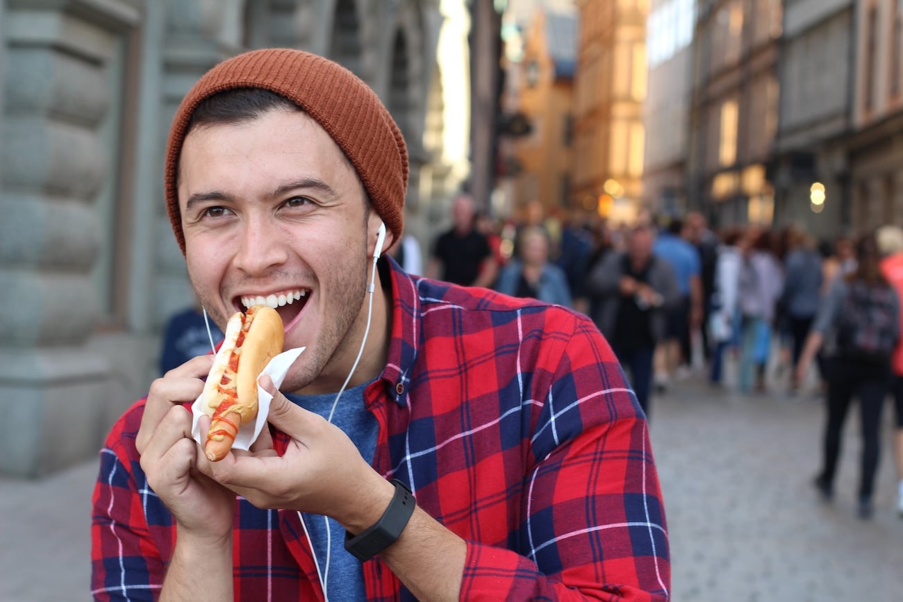 Člověk jí hot dog na ulici
