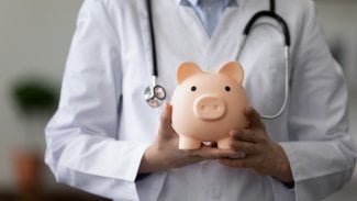 Lékařka drží v ruce růžové prasátko jako pokladničku