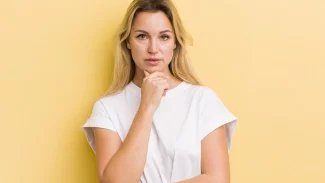 Mladá žena se zamyšleným pohledem podpírající si hlavu rukou