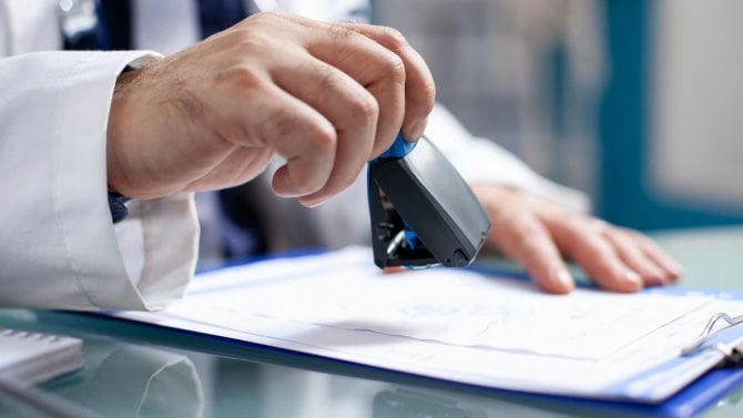 Lékař razítkuje v ordinaci dokument