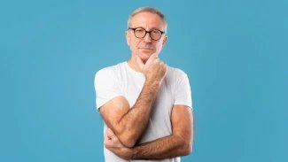 Starší muž v předdůchodovém věku stojí se zamyšleným výrazem