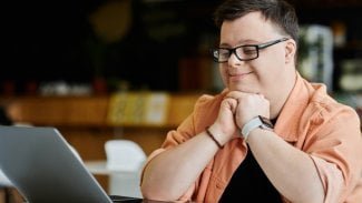 Mladý zněvýhodněný muž spokojeně pracuje u počítače