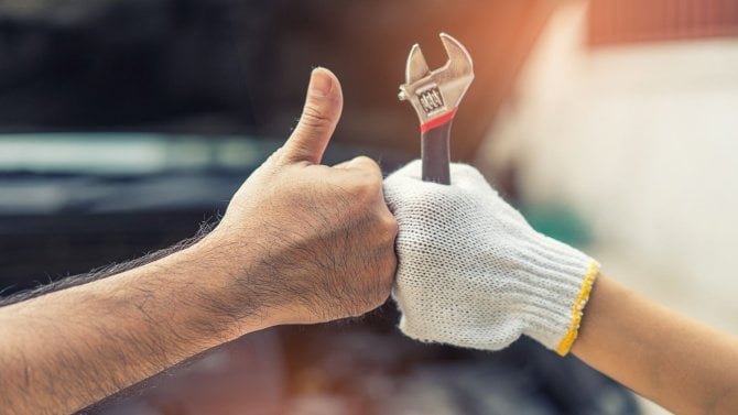 Ruka se zdviženým palcem a ruka opraváře v rukavici s nástrojem