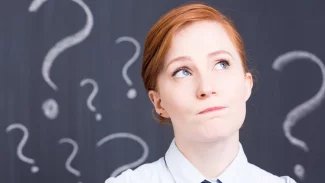 Mladá žena vzhlíží vzhůru se zamyšleným pohledem, Nad hlavou má několik otazníků