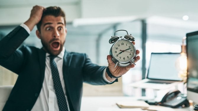 Překvapený muž, který drží v ruce budík