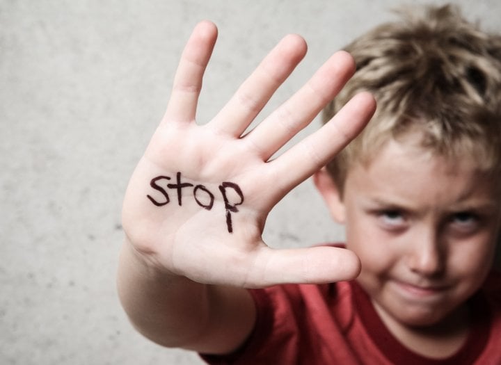 Malé dítě nastavuje dlaň s nápisem STOP