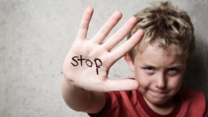 Malé dítě nastavuje dlaň s nápisem STOP