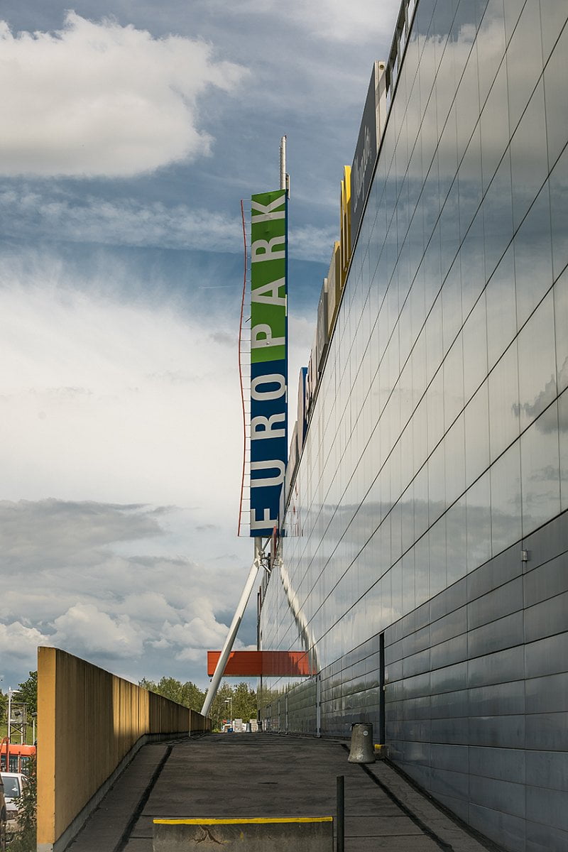 Antény jsou sice umístěny nad reklamním panelem, ale na první pohled celkem nenápadně a tvoří jeden celek poutače pražského obchodního centra. Nevzhledná kabelová trasa je vedena vnitřkem konstrukce.