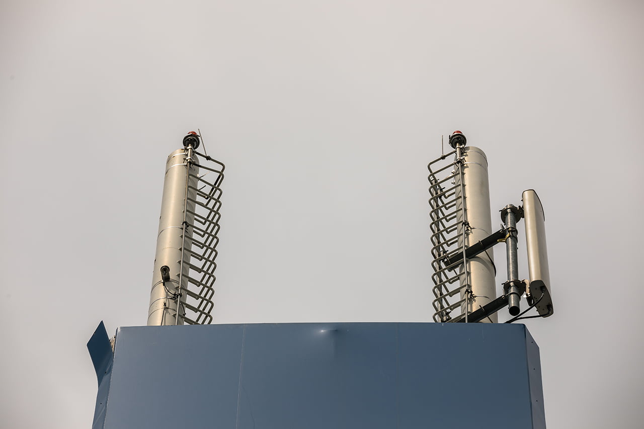 Antény jsou sice umístěny nad reklamním panelem, ale na první pohled celkem nenápadně a tvoří jeden celek poutače pražského obchodního centra. Nevzhledná kabelová trasa je vedena vnitřkem konstrukce.