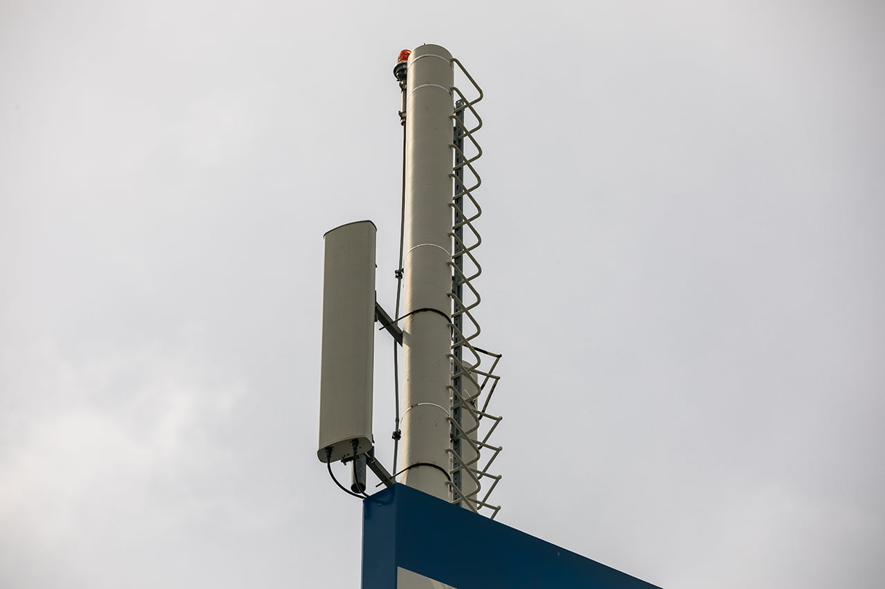 Antény jsou sice umístěny nad reklamním panelem, ale na první pohled celkem nenápadně a tvoří jeden celek poutače pražského obchodního centra. Nevzhledná kabelová trasa je vedena vnitřkem konstrukce.