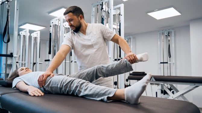 Fyzioterapeut poskytuje rehabilitaci ženě na lehátku