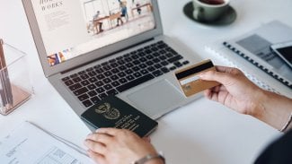 Kancelář - pohled na ruce, počítač a cestovní pas