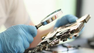Výzkumník v laboratoři zkoumá počítač pomocí lupy