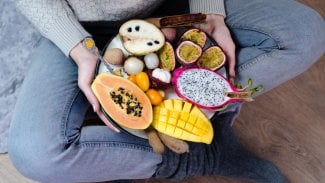 Mísa s exotickým oovocem na klíně ženy