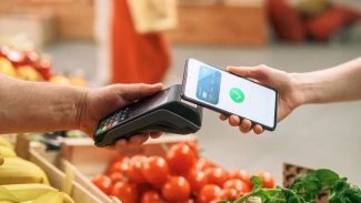 Koncept digitálního bankovnictví: Nakupující používá mobilní telefon s bezkontaktní platební technologií k placení za přírodní zboží na farmářském trhu. Pouliční prodavač držící elektronické online platební zařízení