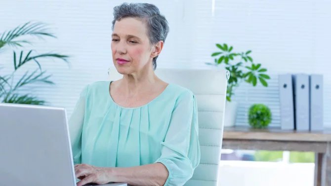 Postarší žena pracující na počítači v kanceláři