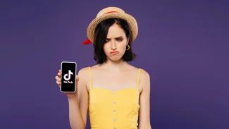 Dívka drží v ruce mobilní telefon s logem aplikace TikTok