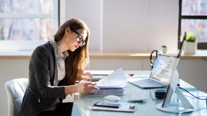 Mladá účetní zkoumá firemní faktury
