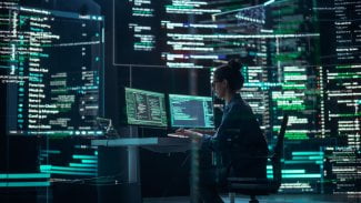 Profesionální programátorka pracující v monitorovací kontrolní místnosti, obklopená velkými obrazovkami zobrazujícími řádky programovacího jazyka. Portrét ženy vytvářející software a kódování.