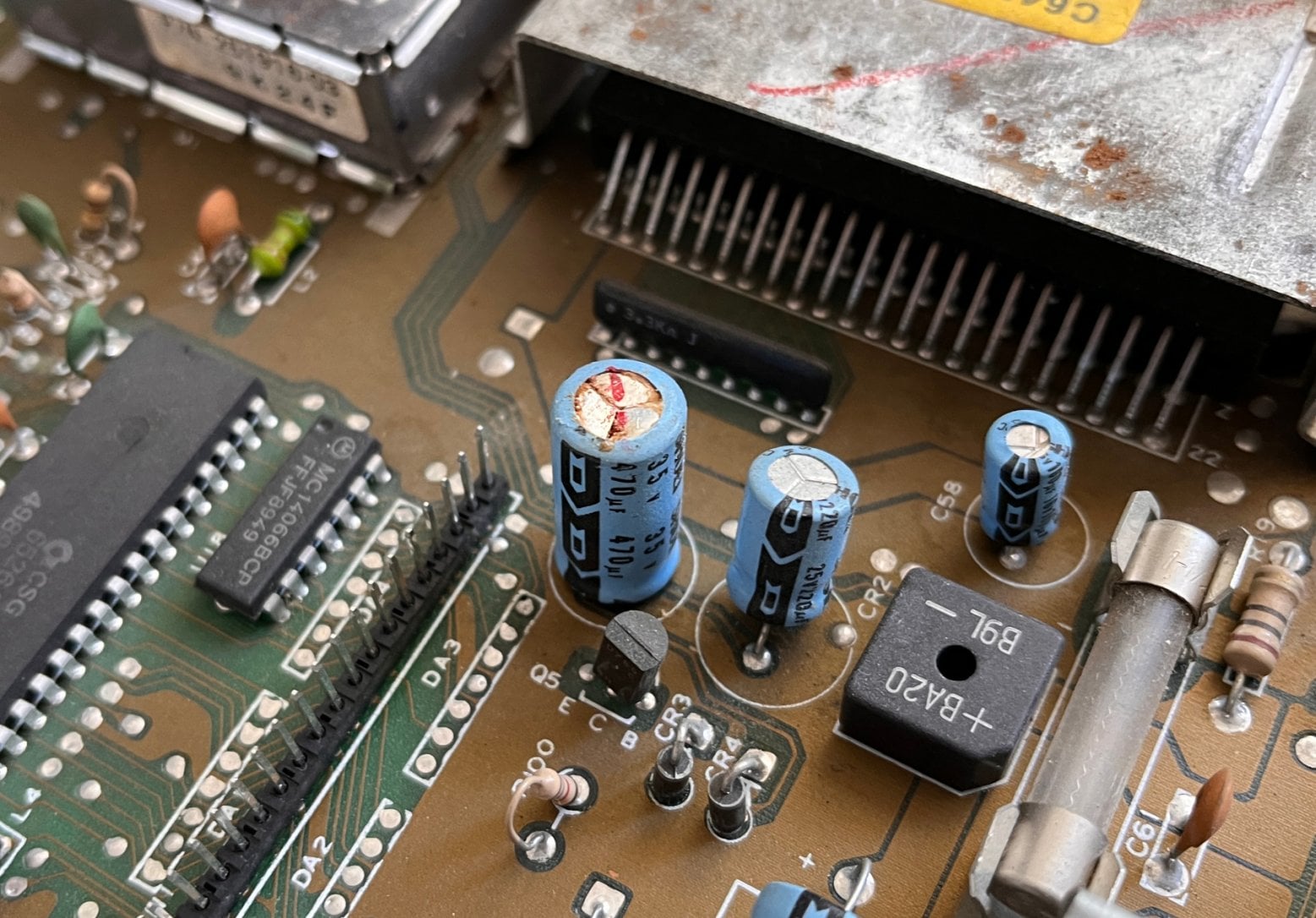 Detail postiženého elektrolytického kondenzátoru. Díra ve víku s jistotou značí, že tomuto kondenzátoru již mnoho kapacity nezbylo.