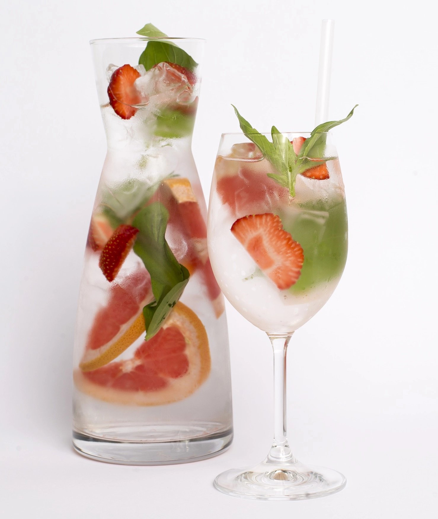 Nealkoholický koktejl s bazalkou a jahodami ve vysoké skleničce na nožce