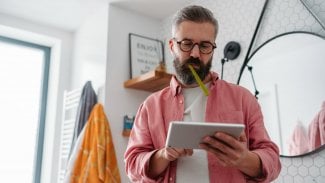 Muž s kartáčkem v puse surfuje na tabletu