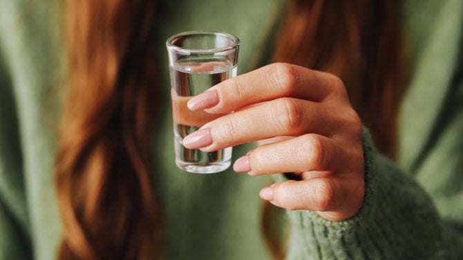 Detail ženské ruky se skleničkou alkoholu