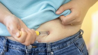 Žena si aplikuje do břicha lék na hubnutí