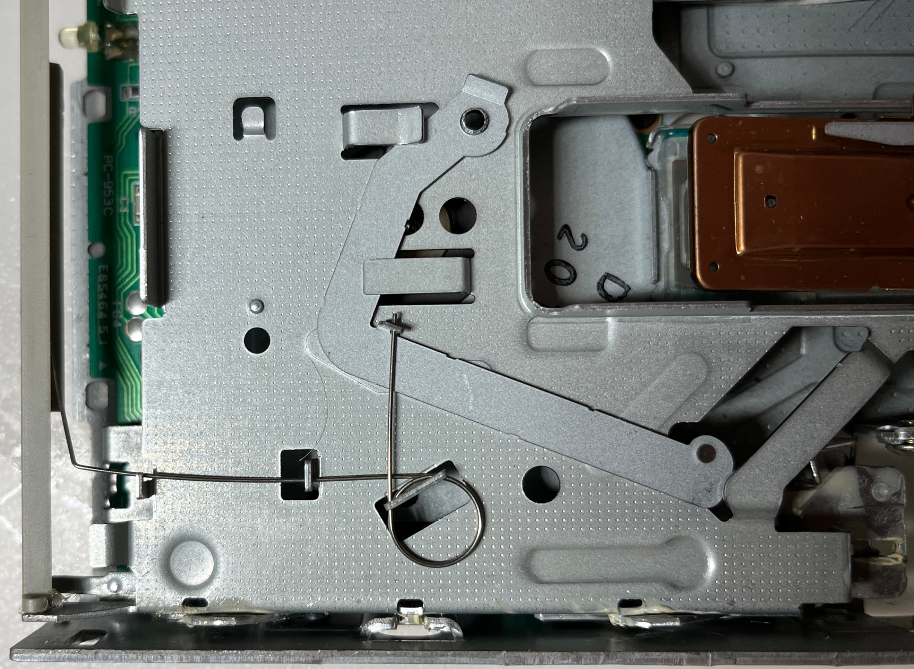 Detail pružiny, která se stará o korektní funkci vkládacího mechanismu a zavírání dvířek. Pro odstraněné mechanismu je nutno tuto pružinu vyjmout.