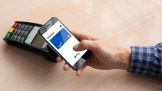 Mužská ruka přikládá mobil k platebnímu terminálu.