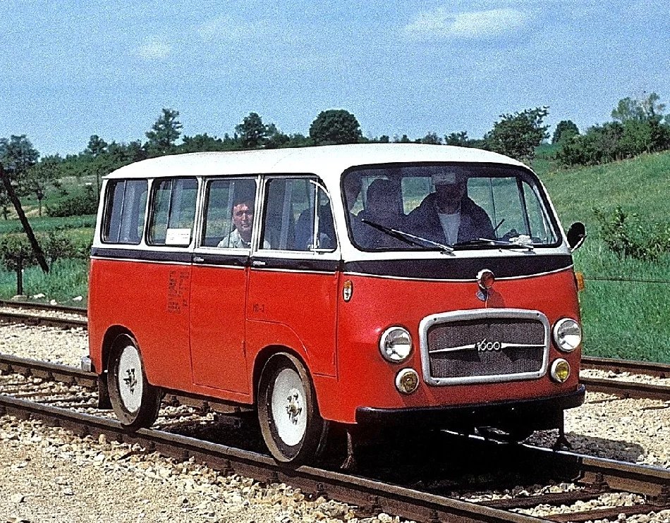 Nezvyklá podoba traťového vozu IMV 1000. Konverzi na železniční vozidlo provedly patrně některé místní železniční dílny, minibus dostal předpisové osvětlení, většinou chyběl volant, pod vozem byla výsuvná točna na obracení vozidla na trati, před předními železničními koly ústí vývody písečníků (proti prokluzu kol)
