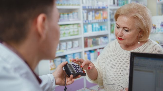 Starší žena platí kartou v lékárně