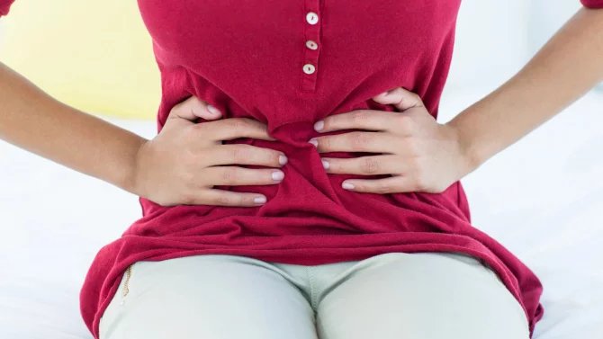 Detail břicha ženy svírané dlaněmi kvůli bolesti
