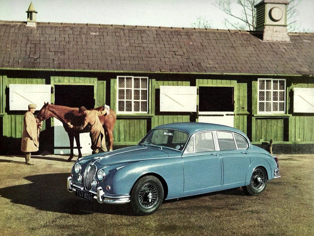 Elegantní pastelově modrá karosérie Mk2 je doplněná koly s drátovým výpletem a centrální křídlovou maticí. Britští čtyřnozí plnokrevníci chybět nemohou a nesmějí…