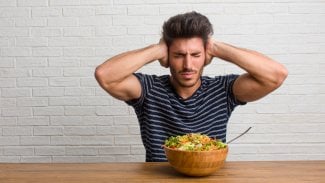 Mladý muž se snaží nad mísou salátu přerušit vtíravé myšlenky na jídlo