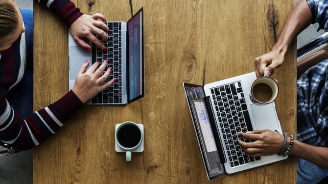 Dva kolegové pracují na svých dvou počítačích