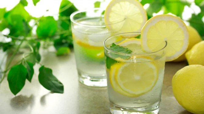 Dvě sklenice s vodou a citrony ozdobené mátou