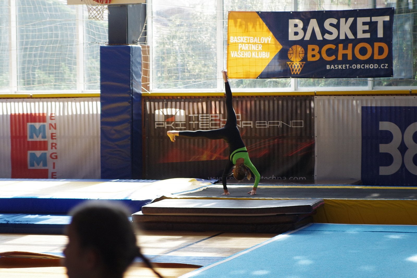 Typická sportovní hala s okny na stěně za cvičenci. Navíc foceno z míst pro diváky. V této situaci si nepomůžete, protože protisvětlo se tlumí bleskem, který nemůžete použít, navíc je to jen na krátkou vzdálenost, ne přes celou halu. (Pentax K-S2, 1/500s f/3,2 ISO400)