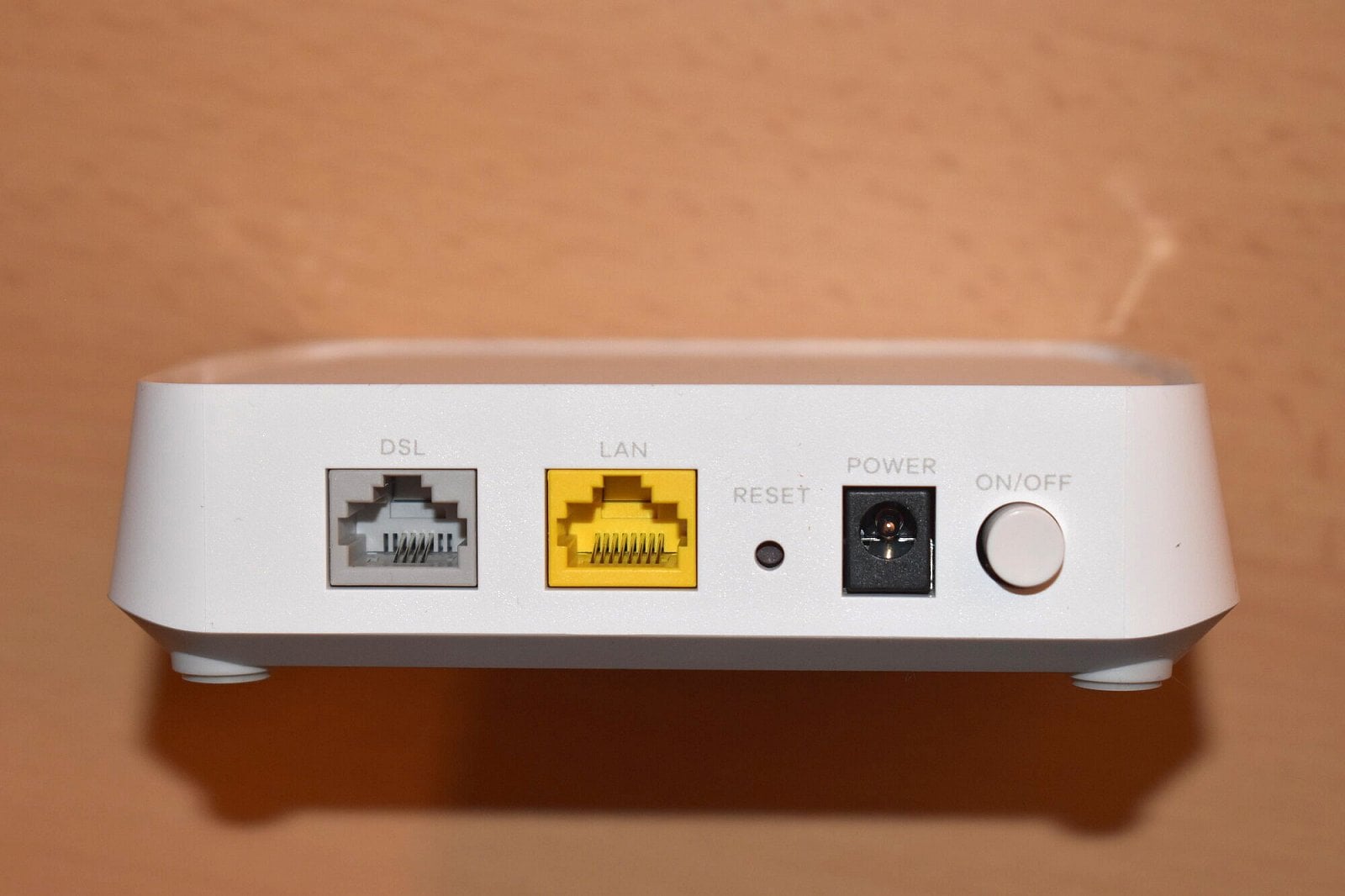 Pohled na konektory, zleva: 8p4c dvoupárové DSL, 8p8c (RJ45) gigabitový Ethernet, tlačítko pro reset, napájecí konektor a zapínací tlačítko