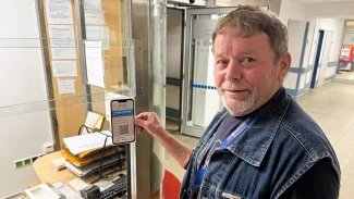 Pracovník nemocnice lepí samolepku s QR kódem pro neslyšící