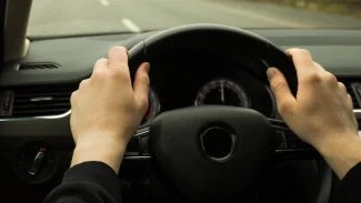 Mužské ruce položené na volantu osobního auta