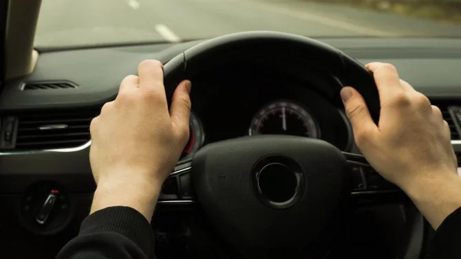 Mužské ruce položené na volantu osobního auta